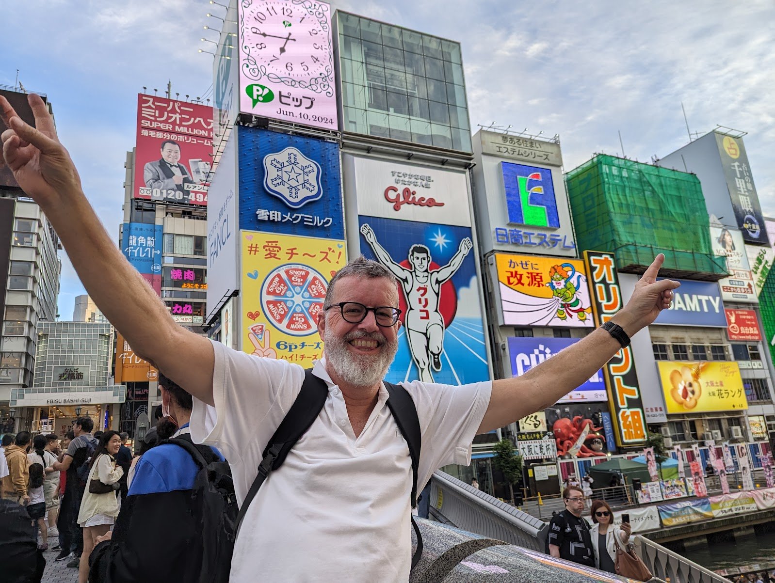 Drew with arms raised in front of the Glico running man sign at Dotonbori, Osaka — June 2024