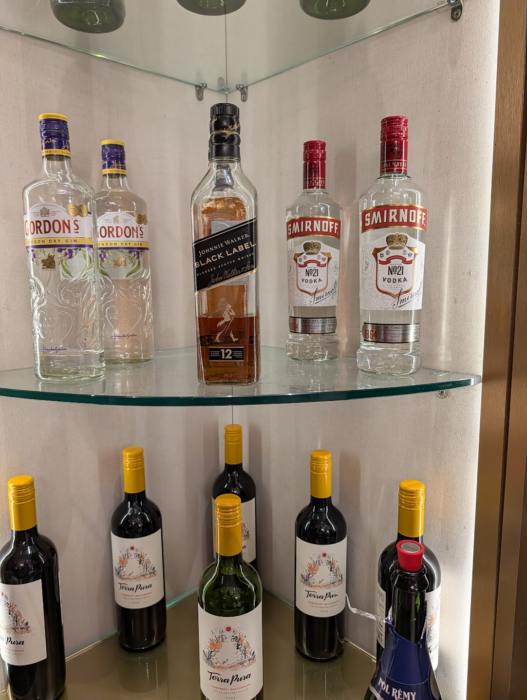 Shelf of spirits including gin, whisky and vodka above a row of red and white wine bottles at SATS Premier Lounge