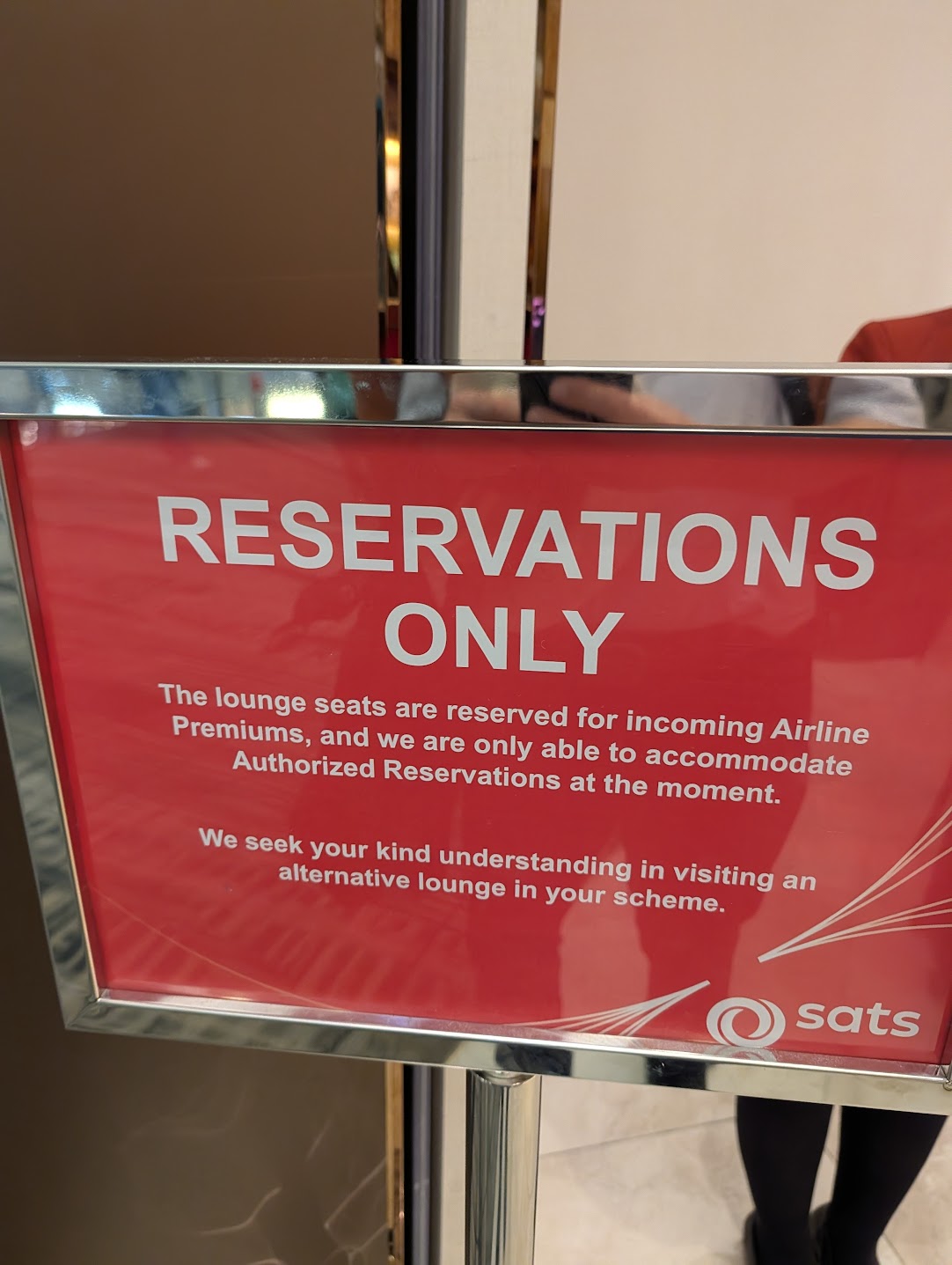 Red SATS sign reading Reservations Only stating lounge seats reserved for incoming airline premium passengers