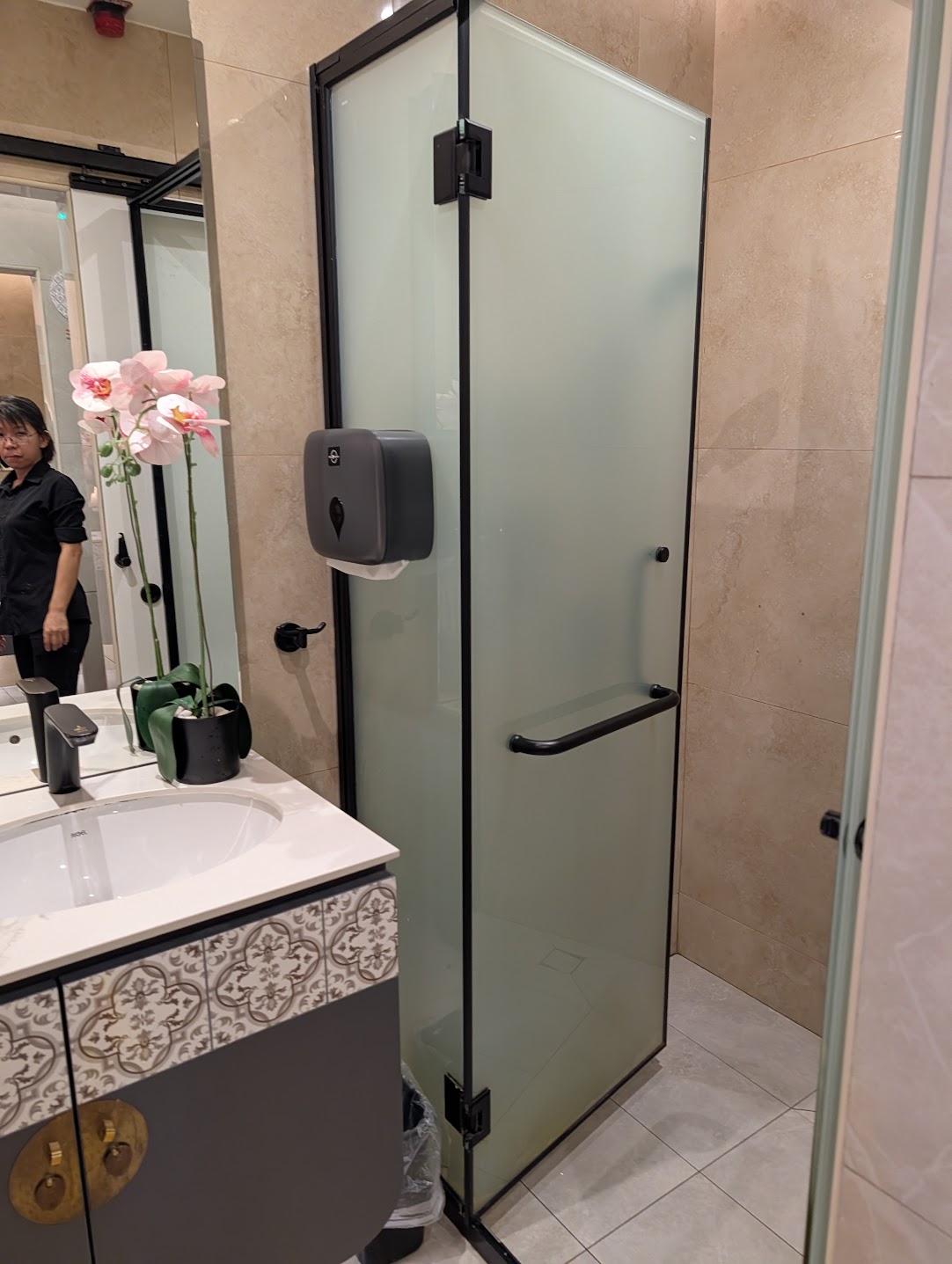 Private shower cubicle with frosted glass door and a vanity with orchids at SATS Premier Lounge Changi