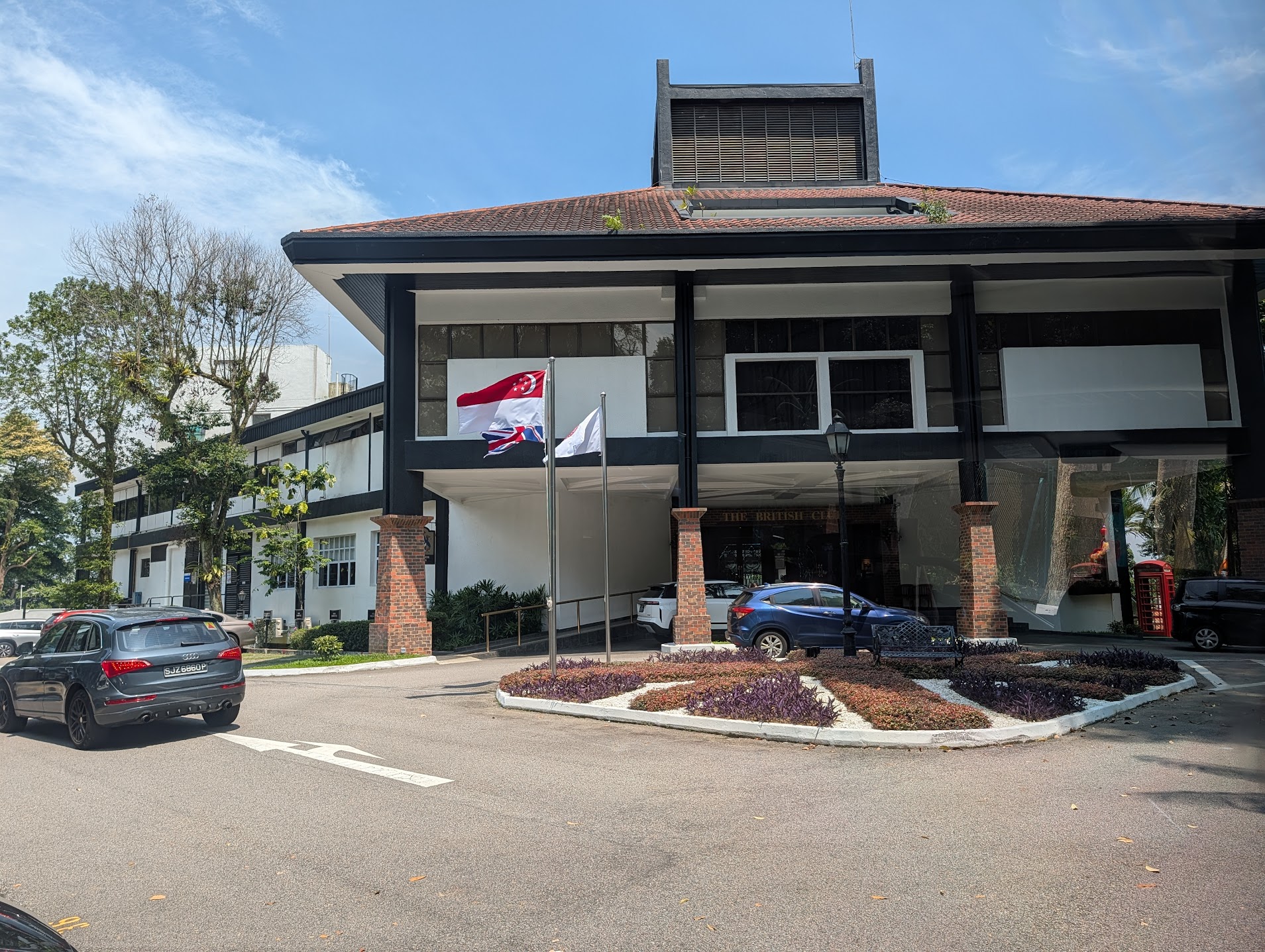 The British Club, Singapore — clubhouse exterior on its hill with Singapore and Union flags