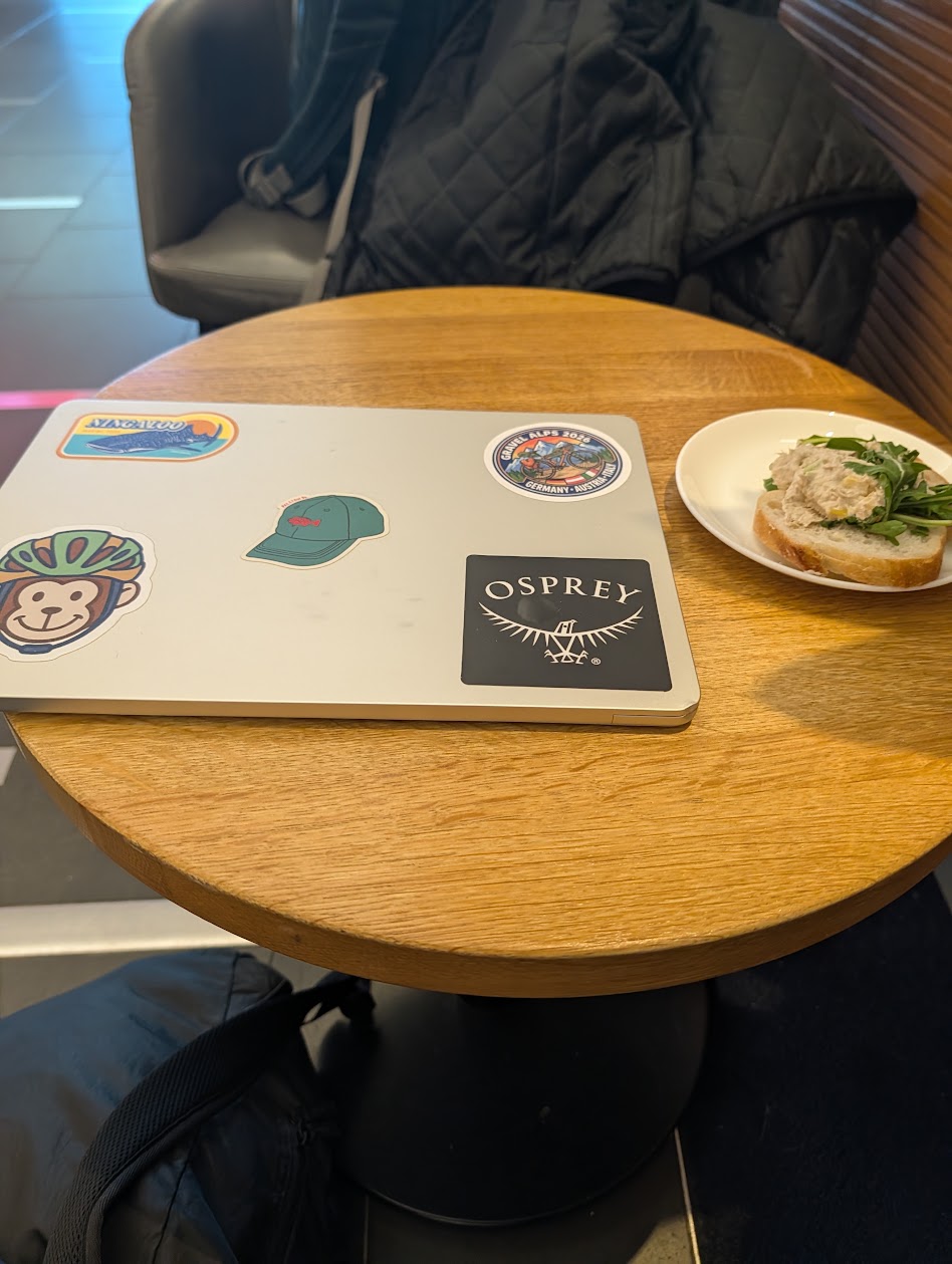 Laptop covered in travel stickers including Gravel Alps 2026 patch