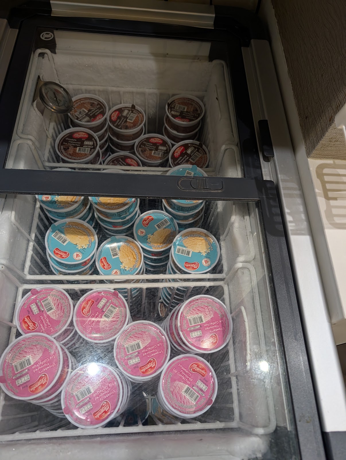 Freezer of Magnolia ice cream tubs in chocolate, vanilla and strawberry