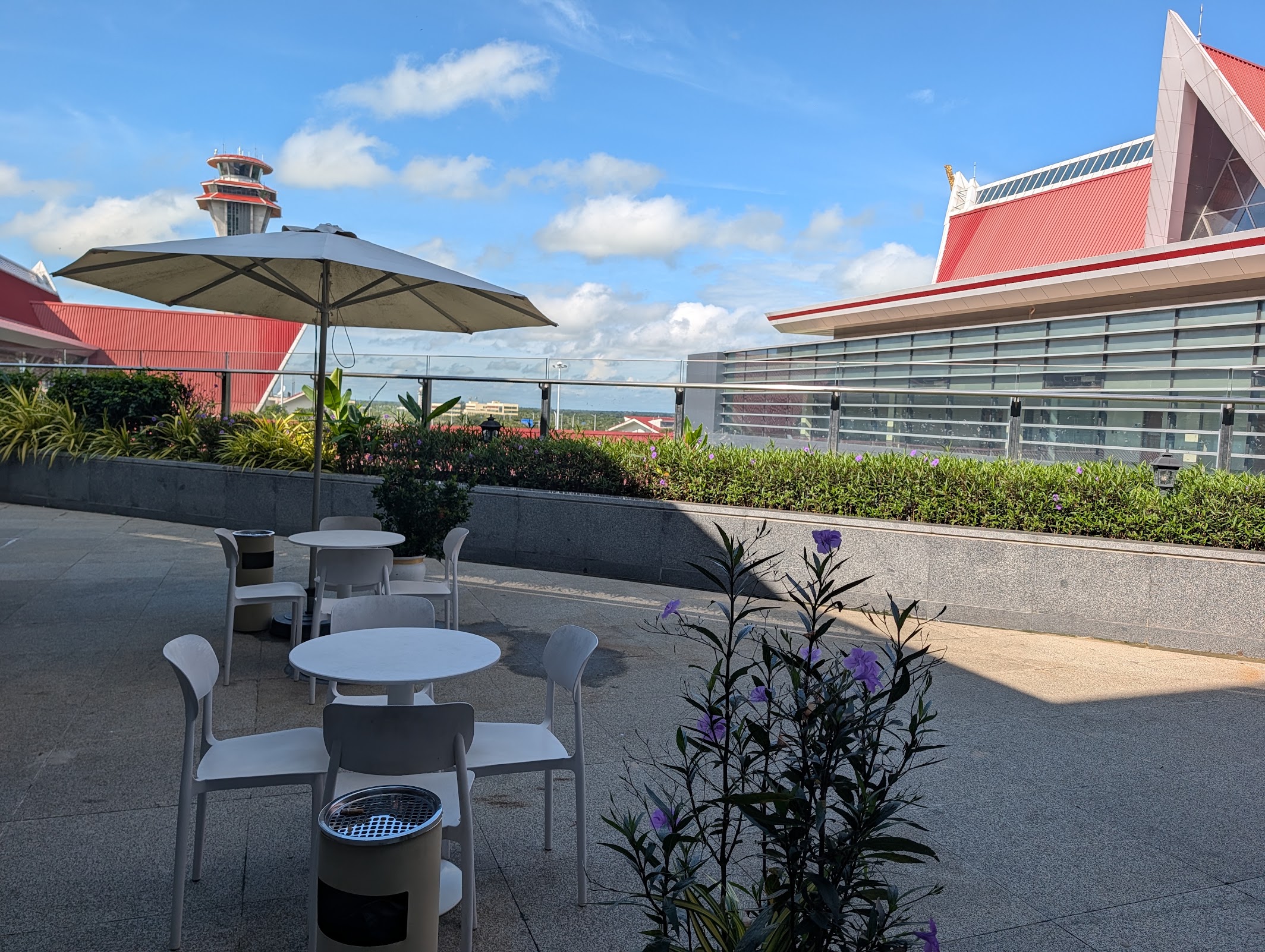 Outdoor terrace with tables, umbrella and control tower view at the Angkor Lounge, Siem Reap